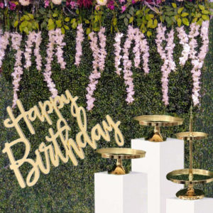 green wall with floral bunch, square plinths and Happy Birthday